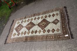 A brown and cream wool rug with border pattern and fringing 82" x 43".