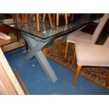 A stylish and contemporary plate glass topped Dining Table standing on 'X' legs,