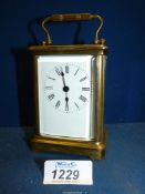 A brass carriage clock with an enamel face having Roman numerals and bevelled glass. No key.