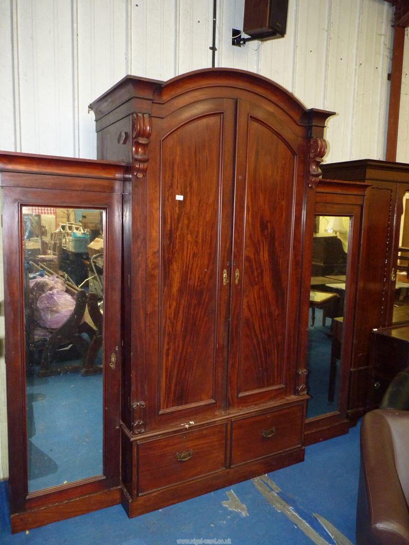 An imposing break-front Mahogany wardrobe the arched centre section having a pair of opposing doors