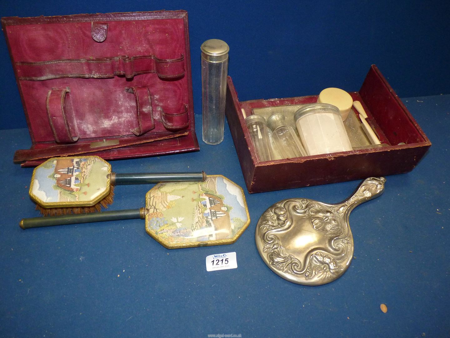 A burgundy leather vanity case with contents a/f., plus embroidered comb and brush set.