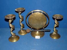 A brass Table Gong with beater and three brass candlesticks.