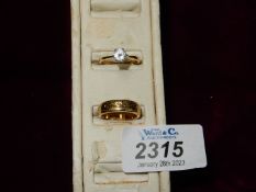 Two gold coloured rings, one having a clear stone Size N, the other with engraved detail Size L.