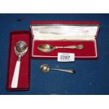 A white metal rattle, a Sheffield silver teaspoon and a plated mustard spoon.