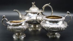 An ornate Silver three-piece Teaset profusely decorated in relief with scroll-work and trailing