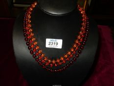 A three string gradient amber coloured necklace.