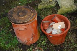 A terracotta bread bin and small concrete filled flower pots.