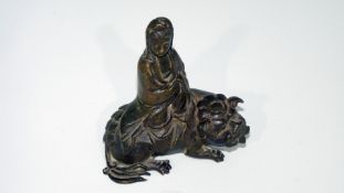 A well-cast Chinese bronze figurine of Guanyin seated on a dog of fo;