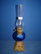 An Oil Lamp with blue glass mantle and metal stand, decorated with boats.