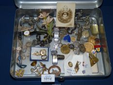 A metal cash tin and contents including military badges, cap badges, old enamelled RAF wings badge,