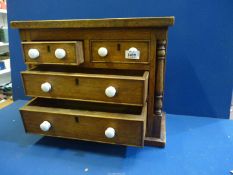 A small Oak miniature chest of drawers with two small over two long drawers having turned pillar