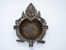 A vintage Tibetan bronze ashtray in the form of a Mahakala, most of the jewelling intact.
