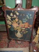 A large Oak framed Firescreen having shaped perimiter and scroll feet with foliage detail,