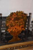A decorative wooden fire screen in the shape of an urn with cottage garden flowers,