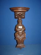 A carved Oak Wall bracket with top support in form of man on altar.