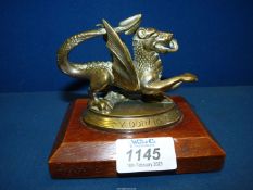 A small brass Welsh Dragon on a wooden plinth with inscription to base 'Y Ddraig Coch A Ddyry