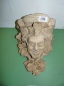 A wall bracket/Corbel featuring a smiling face with trailing flowering stems,