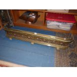 A large Brass fire fender having pierced harp and floral grill with rope effect border, a/f.