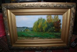 A gilt gesso framed (glazed) painting on board of a rural landscape, signed lower right C.H.