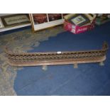 A cast metal fire fender with lion claw feet and pierced grill, 51" long x 9" tall.