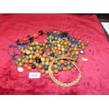 A quantity of wooden beads including black beads, gold coloured braided necklace etc.