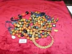 A quantity of wooden beads including black beads, gold coloured braided necklace etc.
