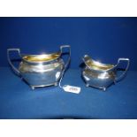 A Silver sugar bowl and matching cream Jug, standing on bun feet having gilded interior,