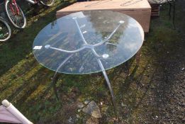 A circular glass topped patio table, 30'' high, x 35 1/2'' diameter.