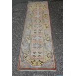 A pink and yellow ground Runner with geometric pattern, fringed, slightly faded,