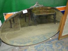 An oval bevelled Wall Mirror with detail to the top, 30'' wide.