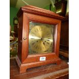 A wooden Mantle clock with brass effect face, with key and pendulum, 11" wide x 6" deep x 15" tall.