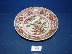 An Anamese polychrome dish painted with a wading bird within floral borders 16th/ 17th century,