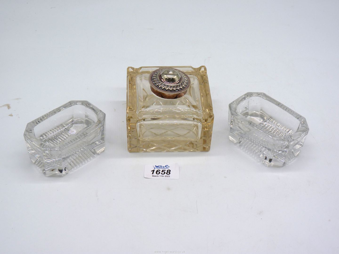 A heavy glass Inkwell with white metal lid and a pair of heavy glass salts.