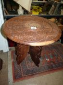 An eastern circular hardwood occasional table on folding legs.