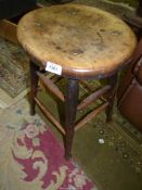 An oval solid seated Stool standing on turned legs and stretchers.