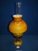 A brass oil lamp with amber glass shade and clear chimney, 23" tall.