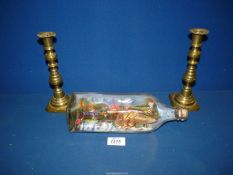 A pair of brass candlesticks and a ship in a bottle.