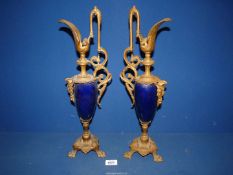 A pair of ornate metal and china Ewers standing on three claw feet, marked "LSF" to base, a/f,