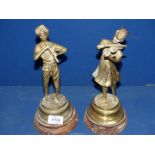 A pair of brass figures of a young couple playing the fiddle and the recorder,
