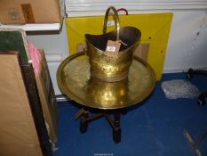 A Brass charger attached to a wooden table base and a brass coal scuttle.