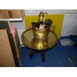 A Brass charger attached to a wooden table base and a brass coal scuttle.