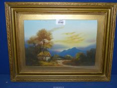 A gilt framed oil painting of a thatched cottage under tall trees with rugged mountains in the