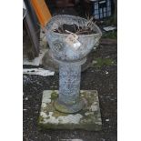 Lead planter and pedestal with lion mask pattern, standing on stone plinth,