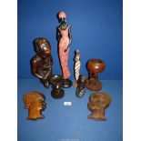 Two wooden face wall plaques, a wooden sculpture of a man sitting with a water flask,