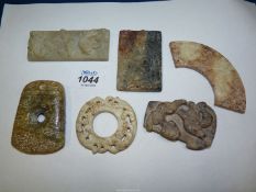 Six small Oriental flat carved stone shapes, shapes to include buckles, pendants, arc shaped,
