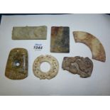 Six small Oriental flat carved stone shapes, shapes to include buckles, pendants, arc shaped,