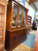 A Contemporary dark hardwood bookcase over cupboard unit having three glazed sliding doors to the