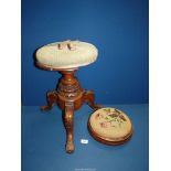 A Victorian revolving Piano stool with green upholstery standing on three carved legs,