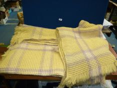 A pair of single waffle blankets, yellow and grey, with fringing.