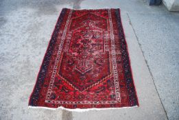 A red woven rug, worn to the centre, 73" x 42 1/2".